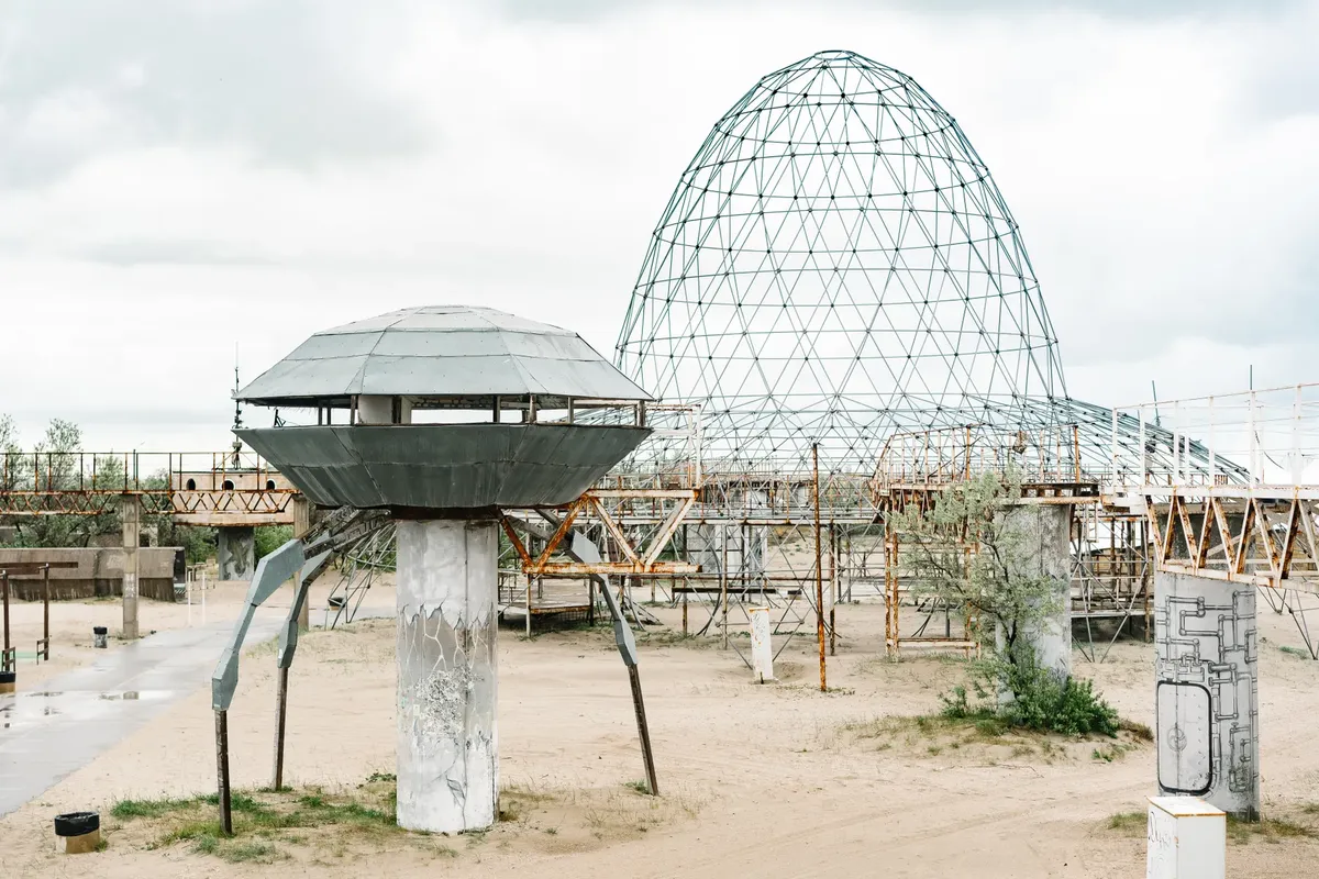曇りの空の下、空しい砂の公園にある金属製のUFOのような構造物